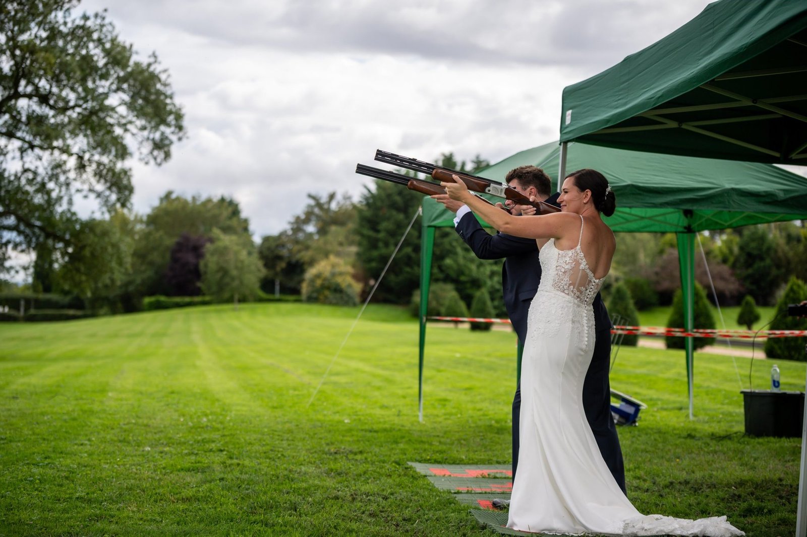 Bride and groom shooting clays side by side on the lawn