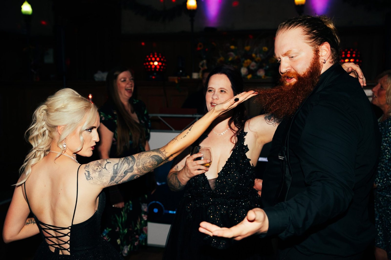Guests on the dance floor, one stroking a groomsman’s red beard